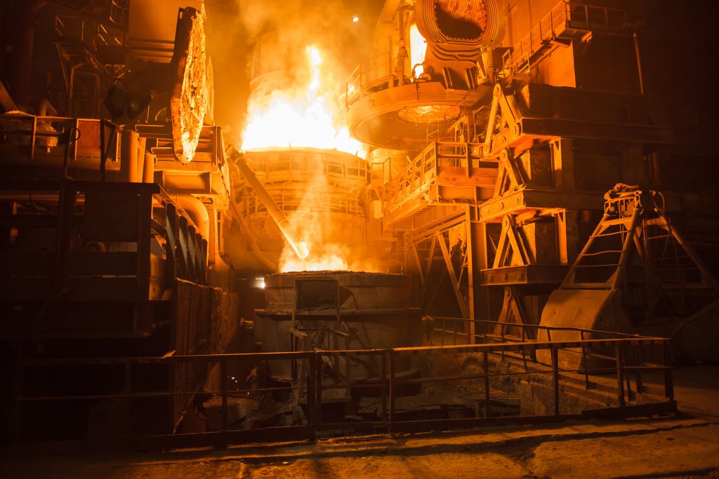 Alto-forno em operação em siderúrgica, com metal líquido incandescente sendo processado.