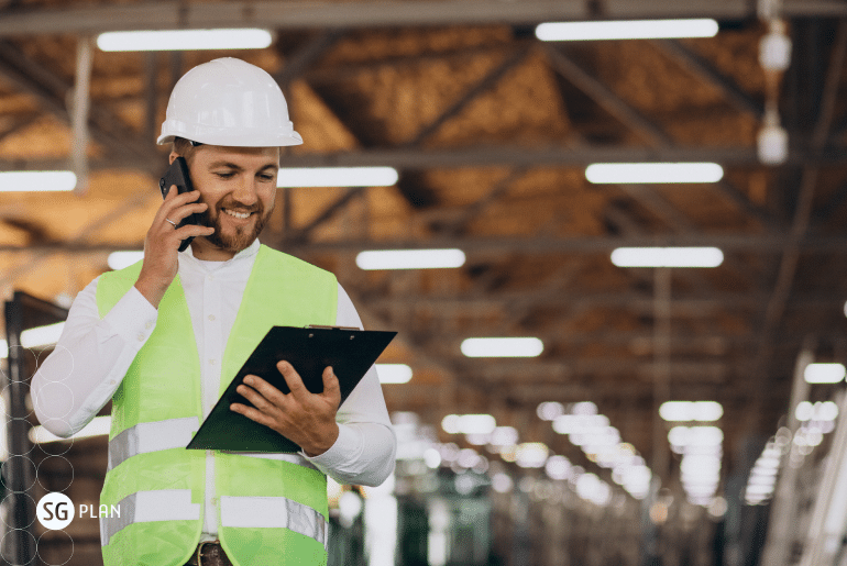 gestor de produção industrial com uma prancheta na mão e falando no celular