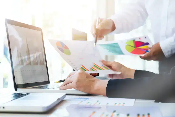 business intelligence homem com camisa branca apontando com a caneta para o gráfico presente na folha que está nas mãos do colaborador
