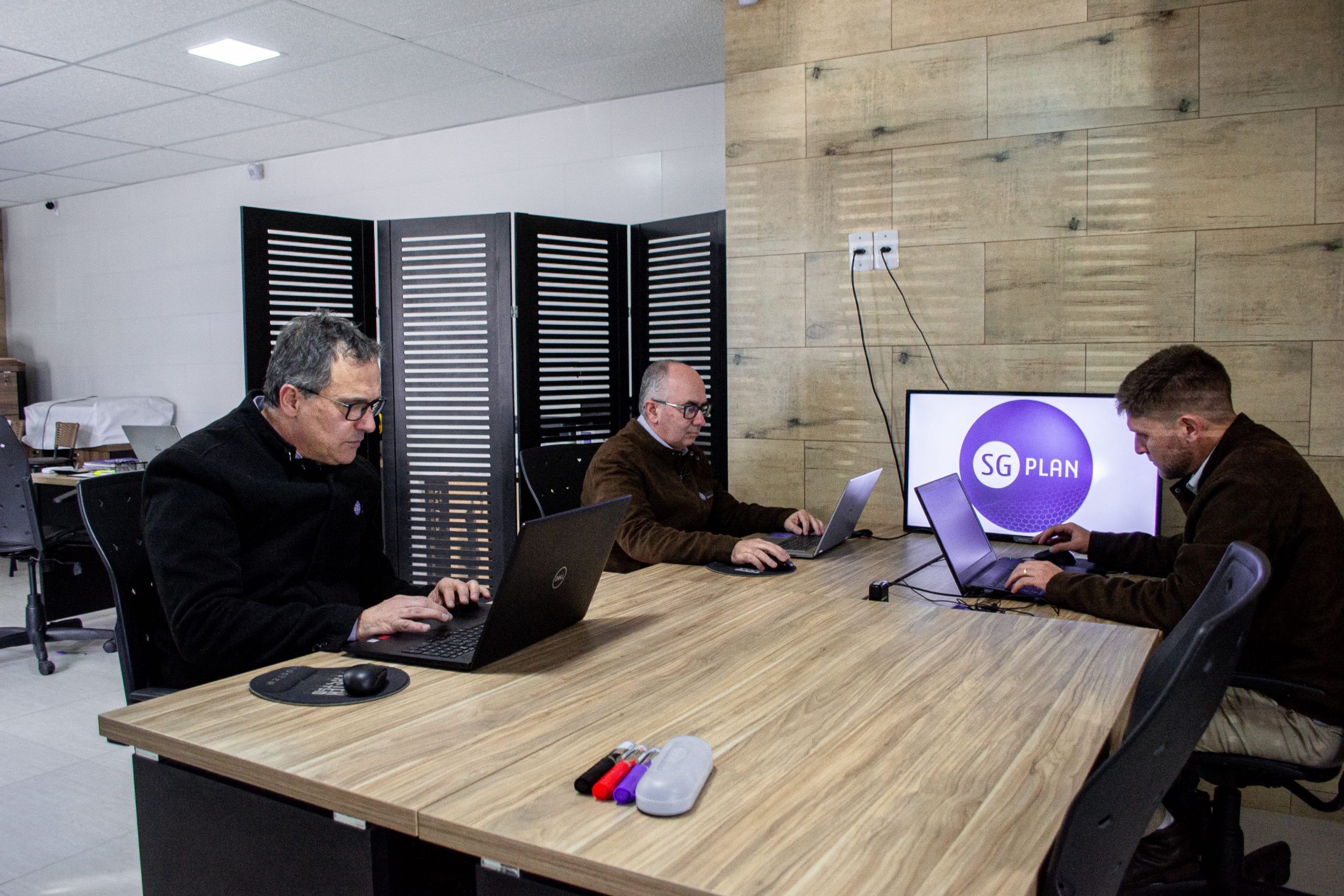 três homens realizando o business intelligence em seus notebooks