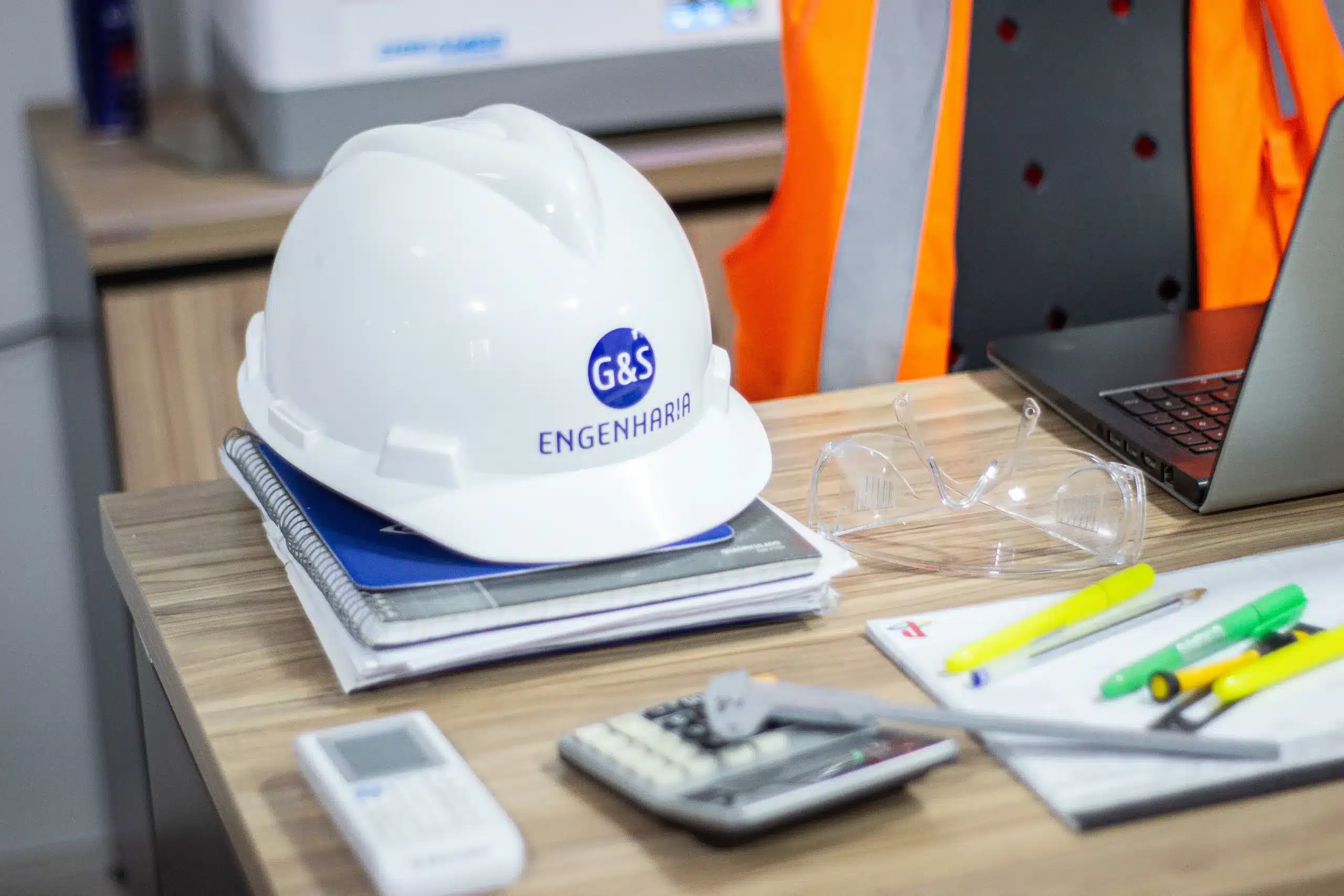 sistema-mes-mesa-de-trabalho-com-capacete-de-seguranca-calculadora-e-papeis.