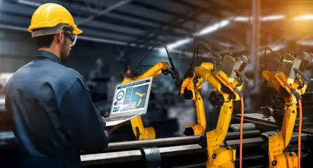 homem com notebook na mão em frente ao equipamento industrial