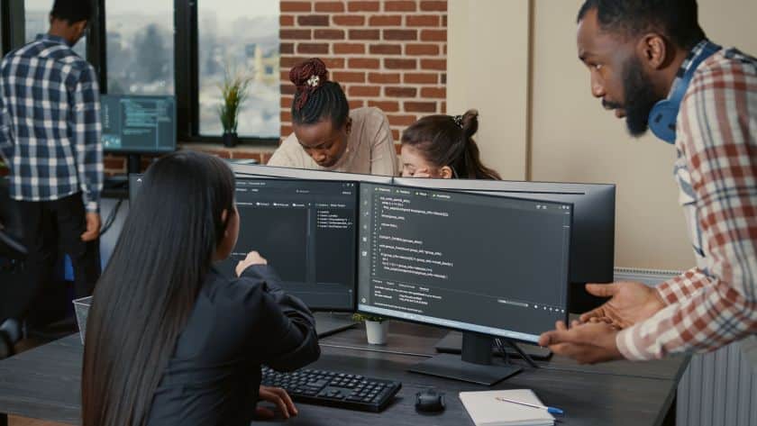 vale-a-pena-investir-em-ti-programadores-trabalhando-em-uma-sala-com-telas