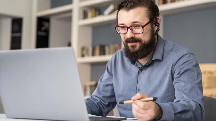 gerenciamento-de-projetos-homem-de-meia-idade-em-frente-ao-notebook-com-fones-no-ouvido-e-fazendo-anotacoes