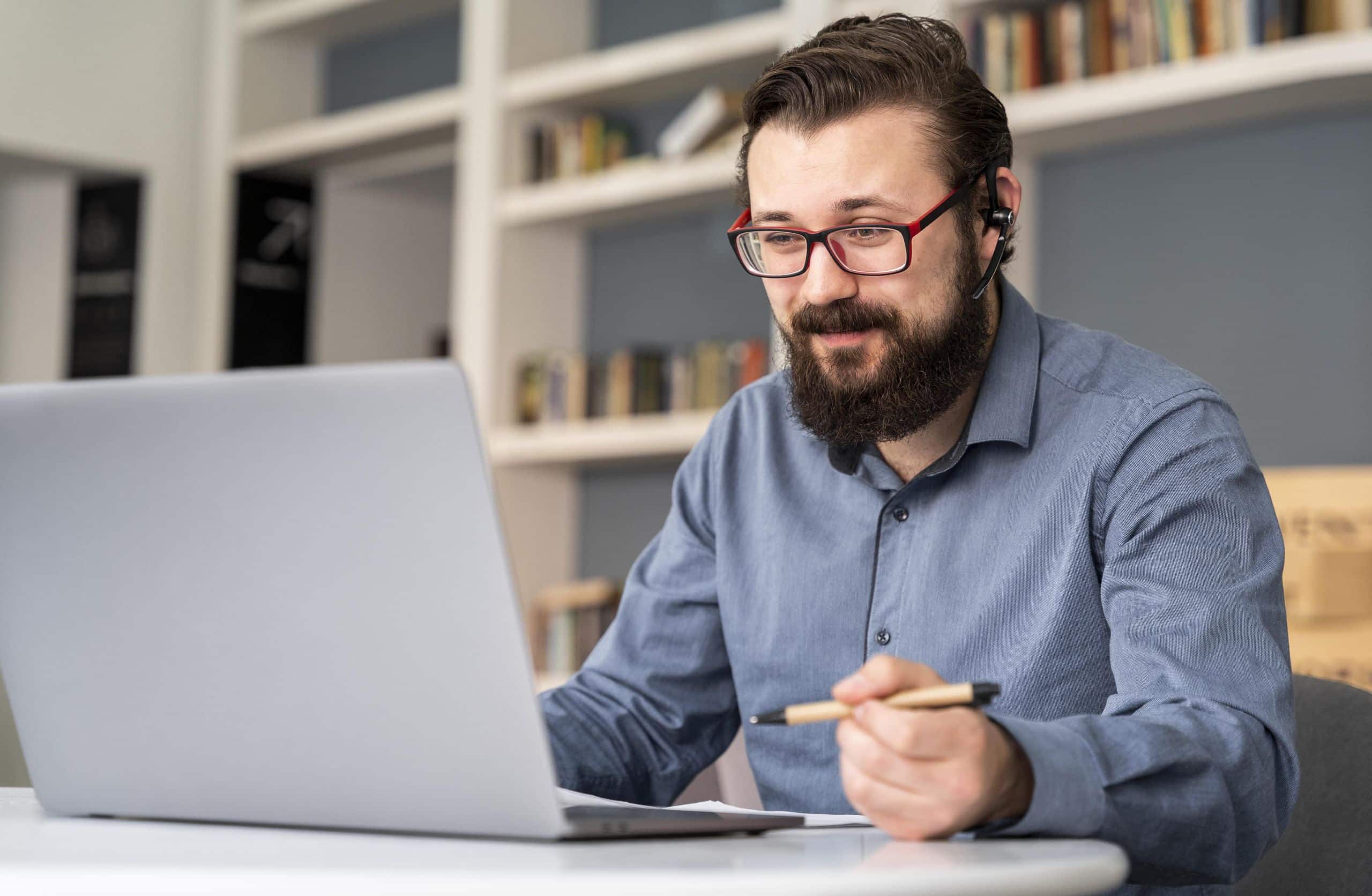 gerenciamento-de-projetos-homem-de-meia-idade-em-frente-ao-notebook-com-fones-no-ouvido-e-fazendo-anotacoes