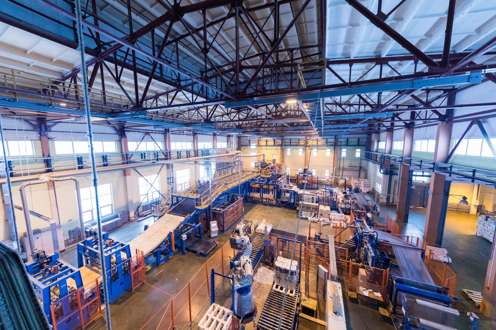 Vista interna de fábrica com esteiras e máquinas industriais em operação.